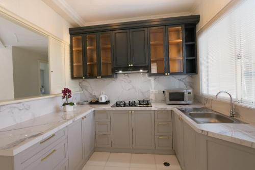 a kitchen with white cabinets and a sink and a microwave at Java Paragon Hotel & Residences in Surabaya