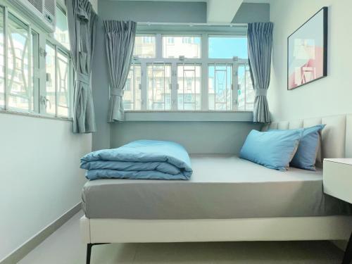 uma cama num quarto com duas janelas em Student Accommodation - 26 Man Yuen Street em Hong Kong