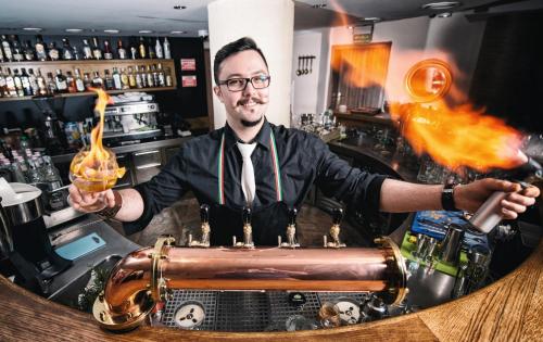a man standing behind a bar holding a drink at Hotel Silvia Gold Gliwice in Gliwice