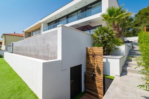 a modern house with white walls and a courtyard at Luxury TABOO Villa & Spa in Medulin for 8 people with heated pool- wellness & sea view in Medulin
