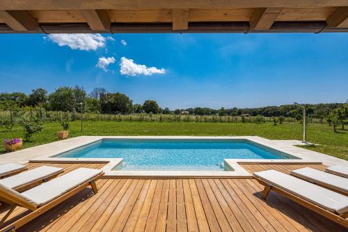 - une piscine sur une terrasse en bois avec des chaises dans l'établissement Villa Campagna near Fažana with 7250m2 large garden and sauna, à Galižana
