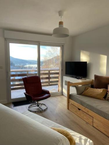 - un salon avec un canapé, une chaise et une télévision dans l'établissement F3 Superbe vue lac, grand balcon, ambiance nature, à Gérardmer