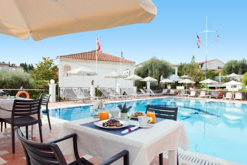 a table with a plate of food next to a pool at Marietta's Resort by Konnect, Gouvia Corfu in Gouvia