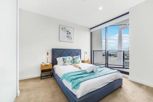 um quarto com uma cama e uma grande janela em Sky-City Apt 3 min to Train & Shopping& Everything em Sydney