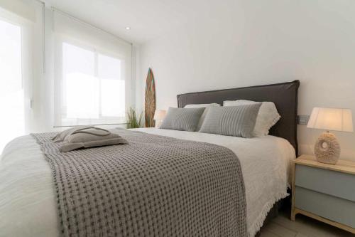 ein weißes Schlafzimmer mit einem großen Bett und einem Fenster in der Unterkunft rentafive Nuevo Parking AA Ascensor in Santa Pola