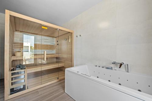 een badkamer met een bad en een glazen douche bij Villa MaEm in Central Istria for families with Sauna, Whirlpool & Sea View in Juršići