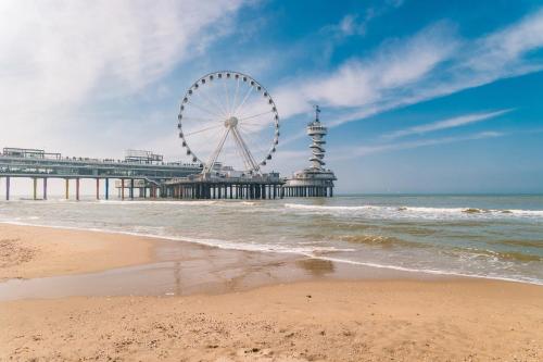 einen Strand mit einem Riesenrad und einem Pier in der Unterkunft Bilderberg Europa Hotel Scheveningen in Scheveningen