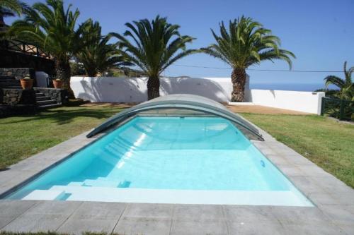een zwembad in een tuin met palmbomen bij Villa Media Luna con vistas a La Palma by Alterhome in La Galga