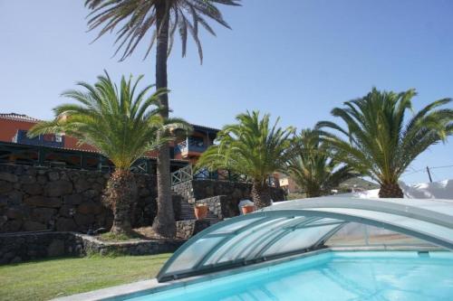 um carro estacionado em frente a uma casa com palmeiras em Villa Media Luna con vistas a La Palma by Alterhome em La Galga