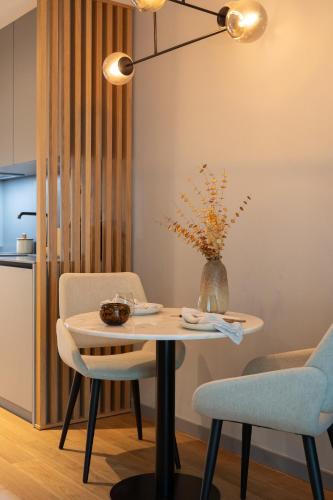 a table and chairs with a vase on it at Nôma Living Icon Apartments in Porto