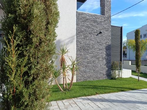 a brick house with a palm tree in the yard at Oikos 9 Rooms and Suites in Nafpaktos