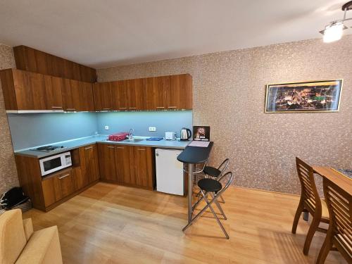 una cucina con armadi in legno, tavolo e sedie di Enjoy Studio and Lovely Apartment Villa Park a Borovets