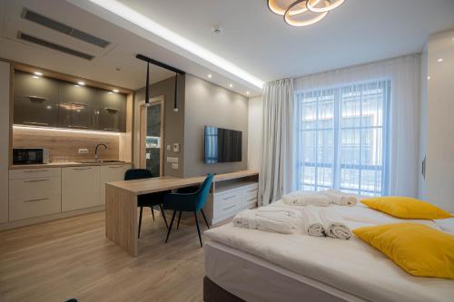 a bedroom with a bed and a desk and a kitchen at Szent Orbán Erdei Wellness Hotel és Residence in Kóspallag
