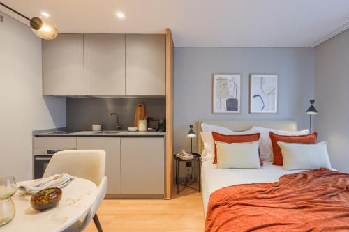 a bedroom with a bed and a table and a kitchen at Nôma Living Icon Apartments in Porto