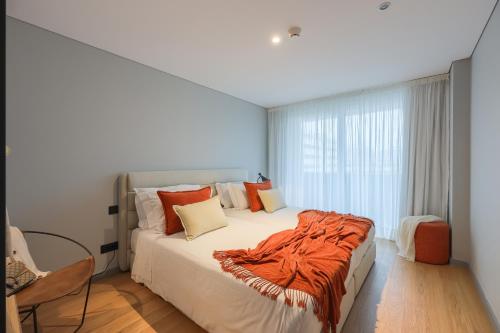 a bedroom with a bed with an orange blanket on it at Nôma Living Icon Apartments in Porto