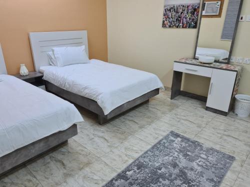 a bedroom with two beds and a desk and a mirror at Ayser 1 in Al Madinah