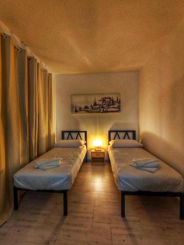 Habitación con 2 camas y lámpara. en Foresteria Del Borgo Etrusco, en Lonato