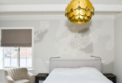 1 dormitorio con cama y lámpara de araña de oro en Herberg de Zwaan Elspeet, en Elspeet