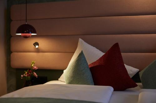 a bed with a bunch of pillows on it at Hotel Metropol by Maier Privathotels in Munich
