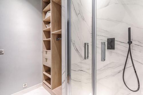 een badkamer met een douche en een glazen deur bij Champs Elysées Marbeuf Magnifique Appartement 4P in Parijs