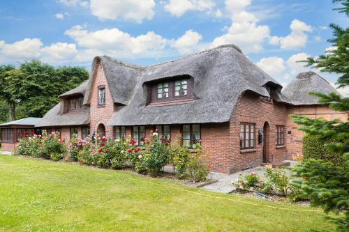 an old house with a thatched roof and flowers at Huldas Hues in Keitum