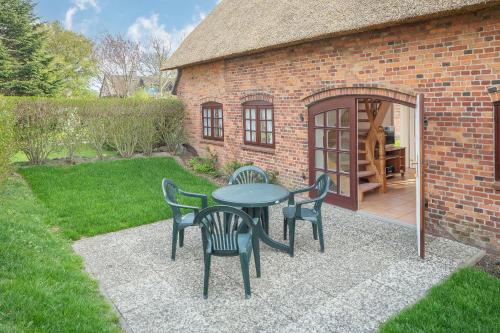 a patio with a table and chairs in front of a building at Kleine Kate in Keitum