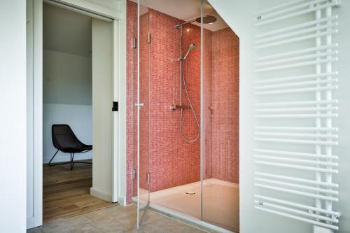 a glass shower in a bathroom with a black chair at Daluja in Keitum