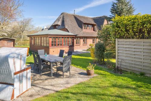 a backyard with a table and chairs and a house at Aalernhues in Keitum