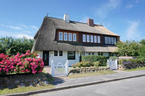 a small house with a thatched roof and flowers at Henning in Keitum