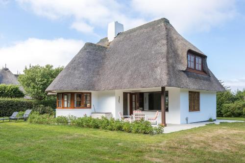 a thatch roofed house with chairs in a yard at Kirchenweg in Keitum
