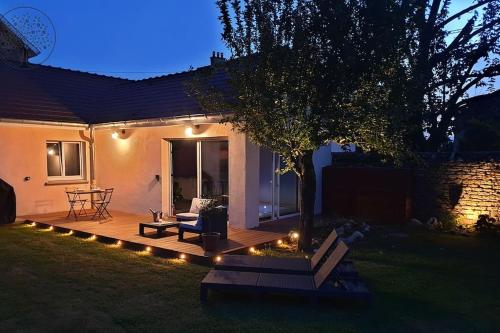 a backyard with a wooden deck with a tree and lights at Guest house avec spa Jura , gîte du petit pommier in Sainte-Agnès