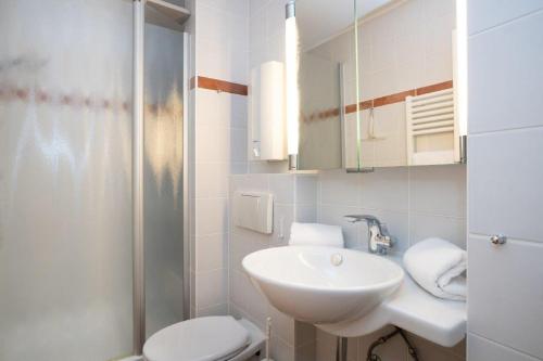 La salle de bains blanche est pourvue d'un lavabo et de toilettes. dans l'établissement Tunghoern Hues Wohnung 07, à Keitum