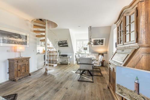 a living room with a wooden floor and a spiral staircase at Takerhof Galerie Wohnung 10 in Keitum