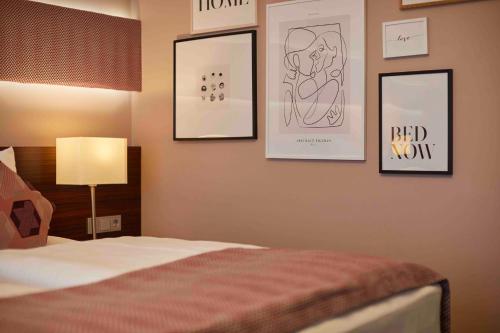 a bedroom with a bed with pictures on the wall at Hotel Metropol by Maier Privathotels in Munich