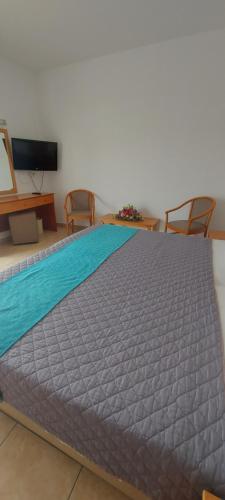 a large bed in a room with two chairs and a tv at New Famagusta Hotel & Suites in Ayia Napa