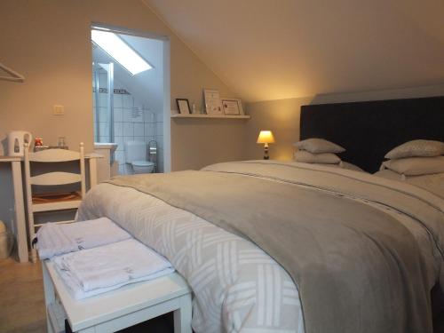 ein Schlafzimmer mit einem großen Bett mit einer Bank daneben in der Unterkunft B&B Le Club de la Source in Hannut