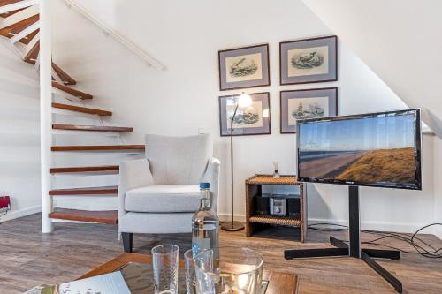 a living room with a television and a chair at Sueder Ech in Keitum
