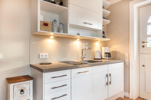 a kitchen with white cabinets and a sink at Gartensuite in Archsum