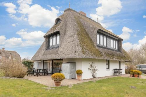 a thatch roofed house with a patio at Uaster Reeg II Maisonette in Archsum
