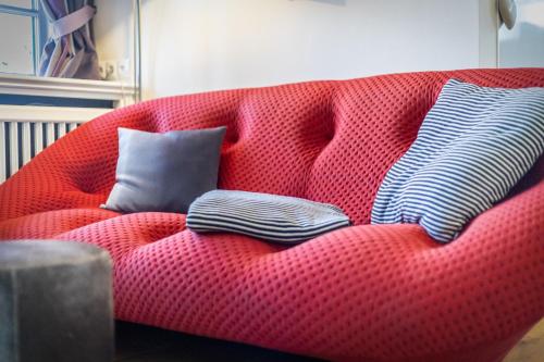 eine rote Couch mit drei Kissen drauf in der Unterkunft Kleines Nest (Wattküken) in Keitum