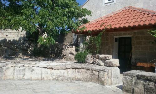 a house with a stone wall next to a door at Fishing Family House in Čilipi