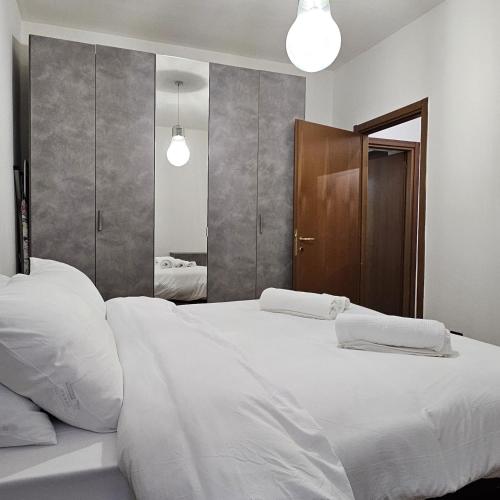 een slaapkamer met 2 witte bedden en een spiegel bij Casa Moderna Olgiate in Olgiate Olona