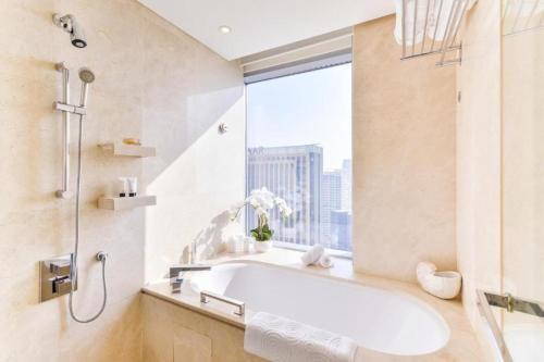 a bathroom with a bath tub and a window at Address Marina Suites in Dubai