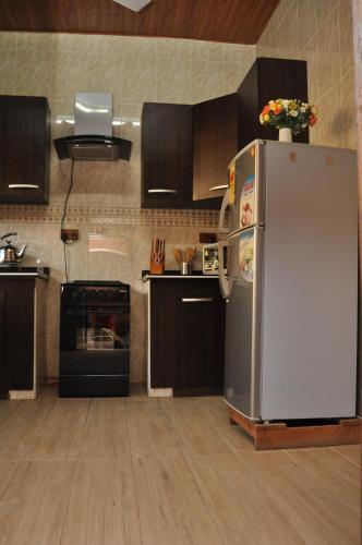 a kitchen with a stainless steel refrigerator and a stove at Santa Monica Home Lodge in Senchi
