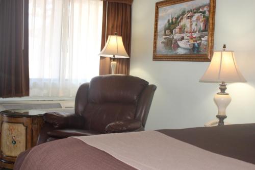 a bedroom with a bed and a chair and a lamp at O'Cairns Inn and Suites in Lompoc