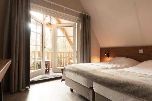 een slaapkamer met een bed en een groot raam bij 't Eekhoornnest in Soest