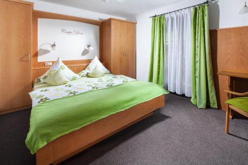 ベルヒテスガーデンにあるPension Rennlehen Ferienwohnungenのベッドルーム1室(緑のシーツが敷かれたベッド1台、窓付)
