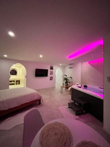 a bedroom with a bed and a bathtub with pink lights at La Suite du clocher in Noves