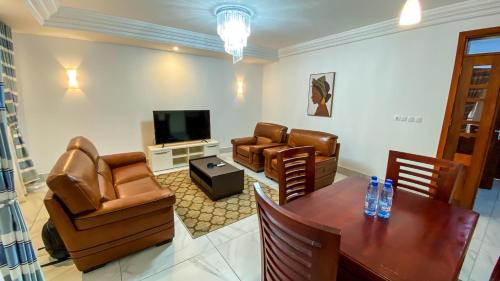 a living room with a table and chairs and a television at BELMANN BONAPRISO in Douala