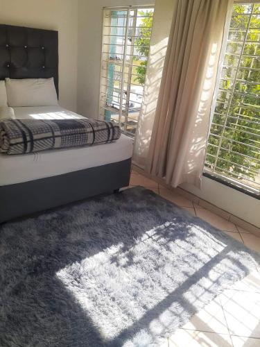 a bedroom with a bed and a rug and a window at HUNTERS NEST GUEST HOUSE BRONKHORSTSPRUIT in Erasmus